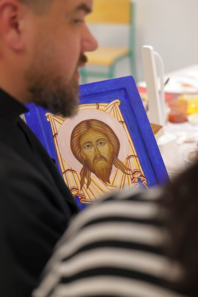 Instruktor w czerni trzymający deskę z ikoną Chrystusa.